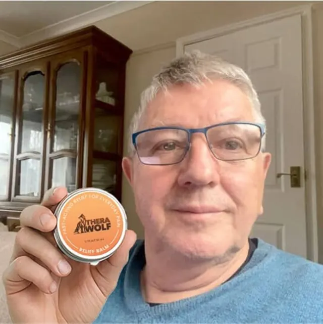 A TheraWolf customer holding his jar of balm